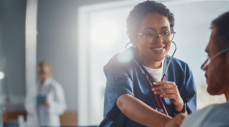 female nurse checks heartbeat of male patient using stethoscope